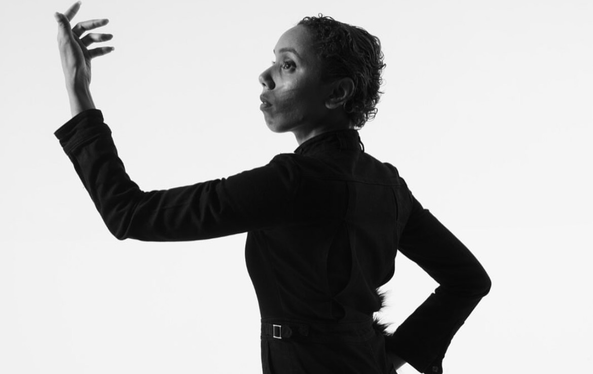 Black-and-white close portrait of a performer raising one hand