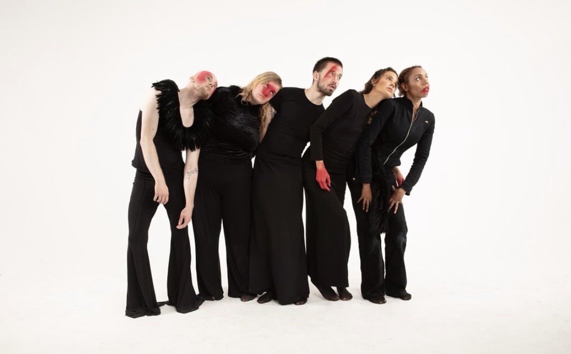 Five performers leaning as a linked line against a white background