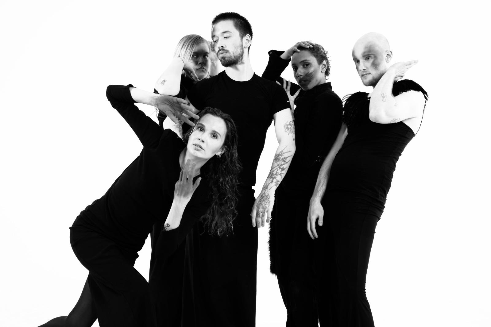 Five performers gathered in a close black-and-white portrait