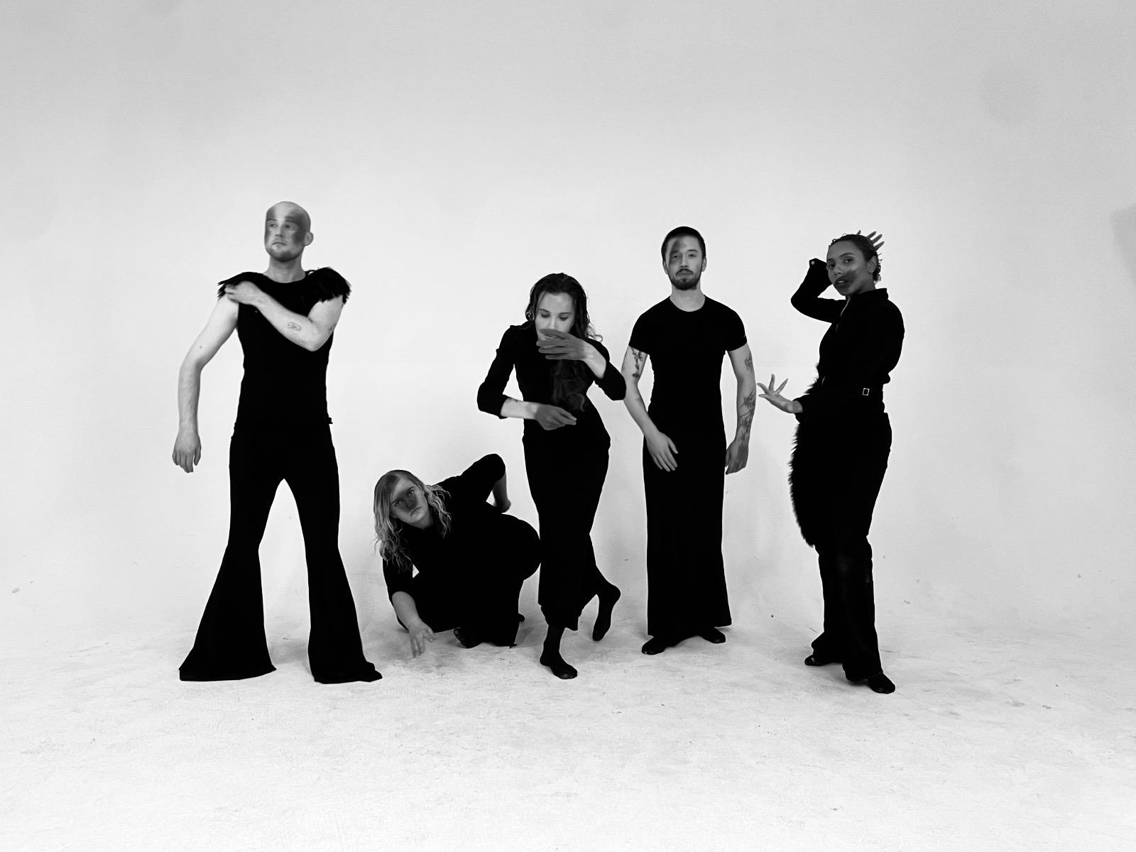 Five performers holding distinct sculptural poses in the studio