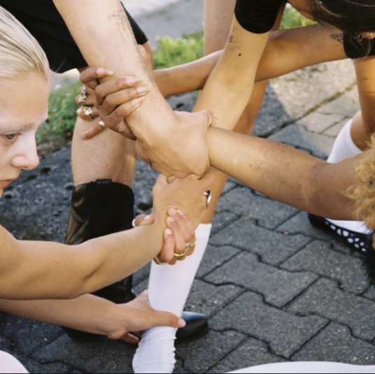 Performers linking hands and arms into a shared structure