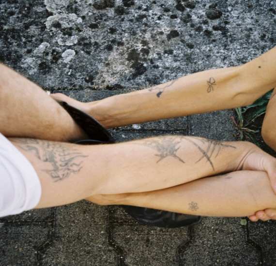 Tattooed legs layered together on the ground