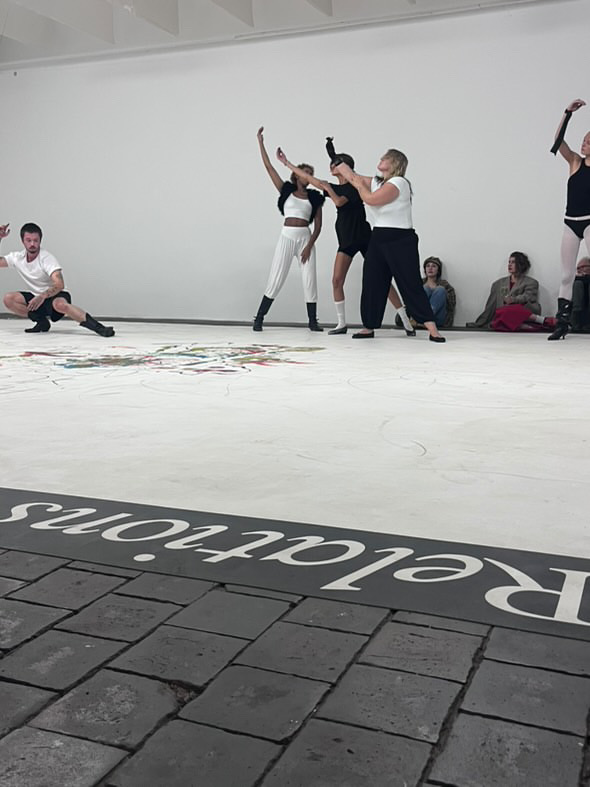 Performers reaching upward while others remain close to the floor