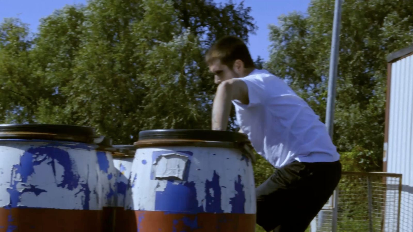 Performer moving between painted industrial barrels