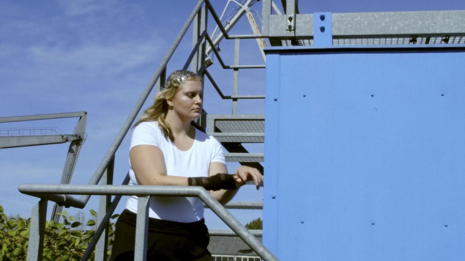 Performer framed by blue industrial architecture