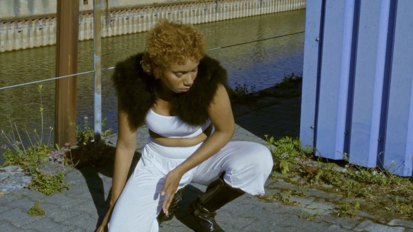 Performer crouching beside the river