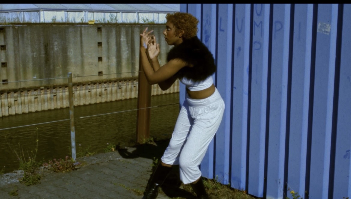 Performer raising both hands beside the blue wall