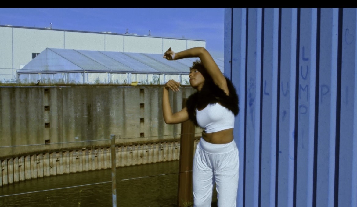 Performer arching through a gesture beside the blue wall