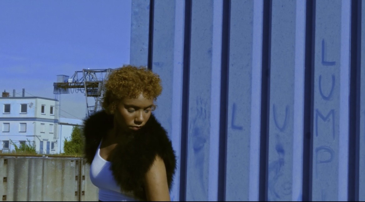 Performer moving in front of a blue corrugated wall
